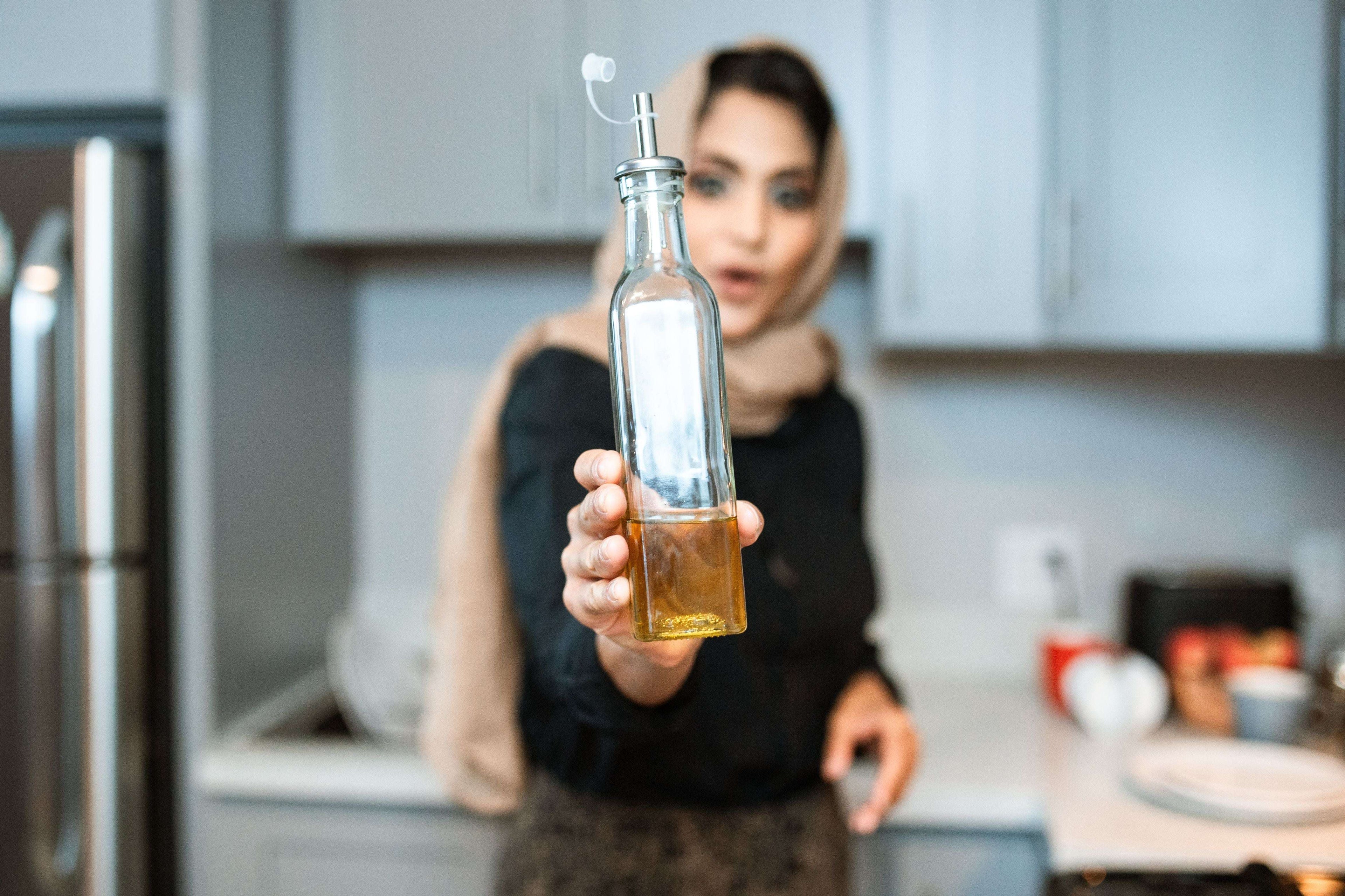 A lady in the kitchen holding a bottle of seed oil - posing the question - Are Seed Oils Bad for You? What the Science Actually Says - and Why Ratio Matters More Than Ingredients