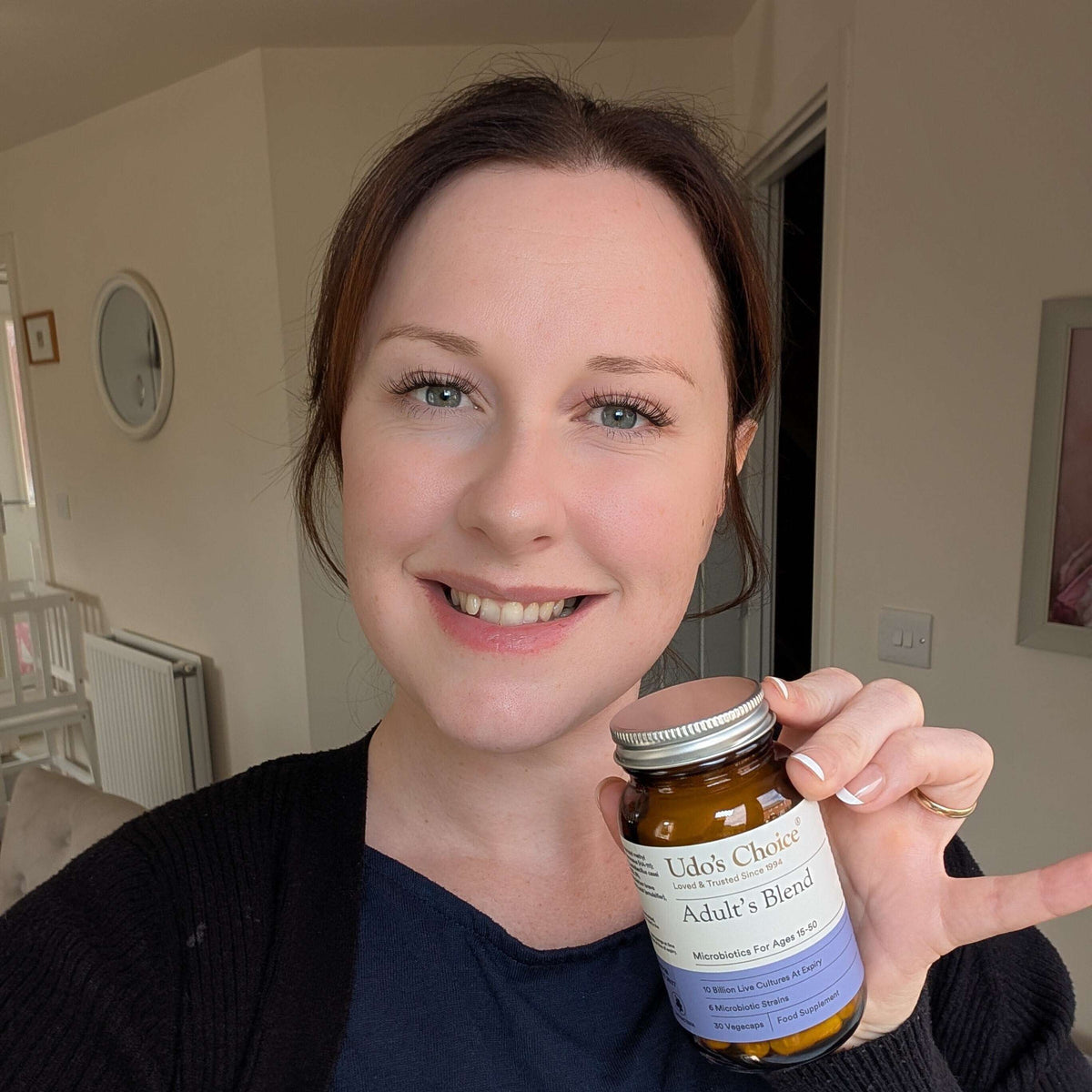 A healthy woman holding Udo's Choice Adult's Blend Probiotic at home