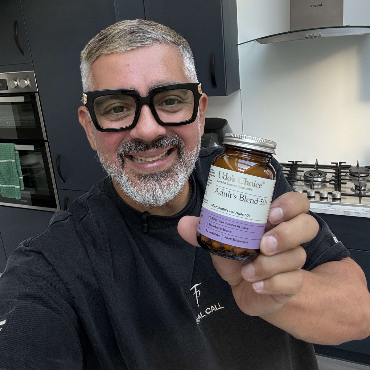 A man wearing glasses in his 50s holding a bottle of Udo's Choice Adult's Blend 50+ Probiotics 