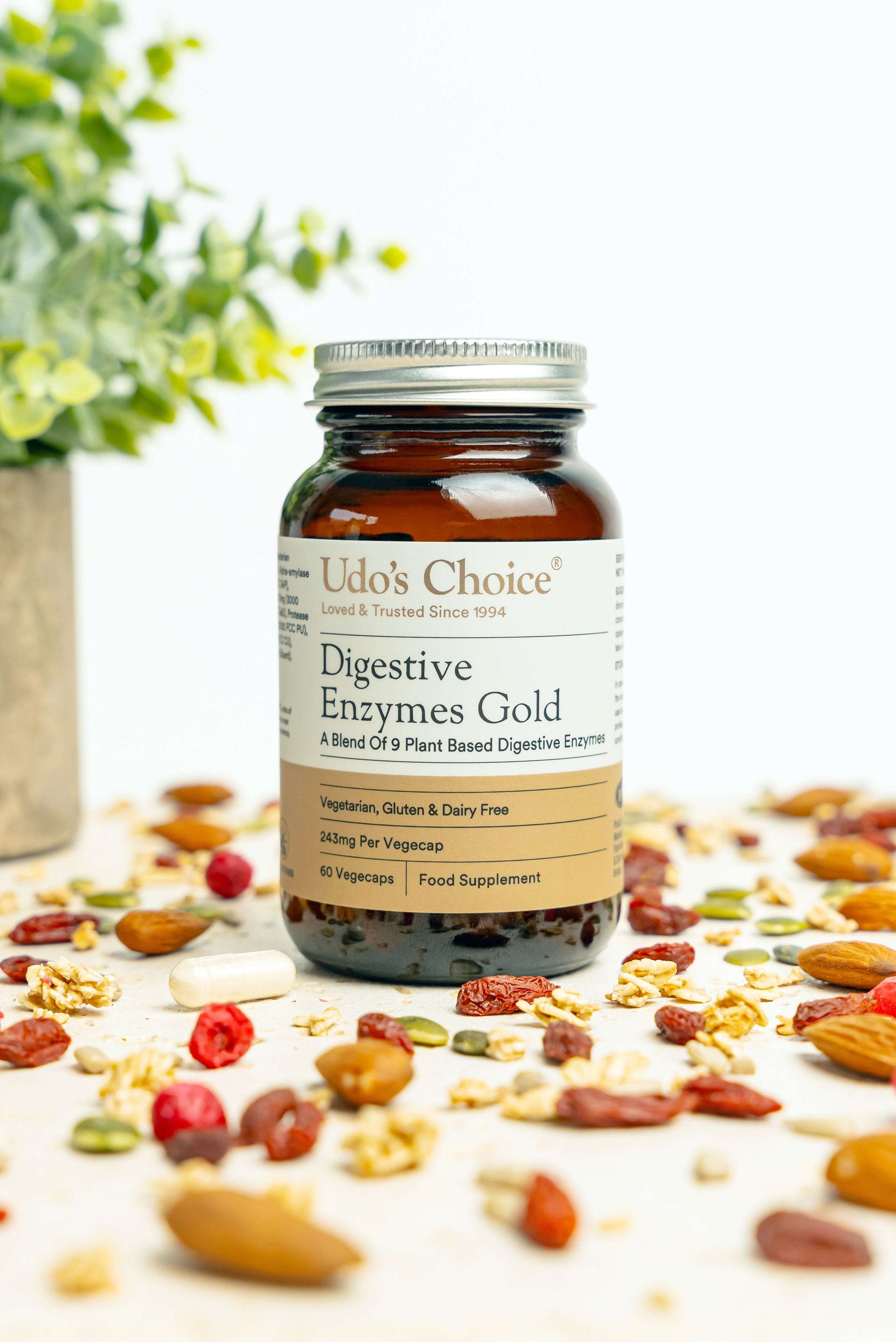 Bottle of Udo's Choice Digestive Enzymes Gold on a surface with dried fruits and plants.